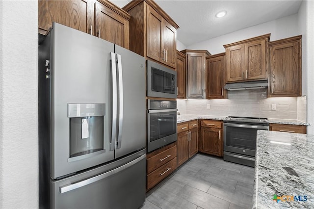 3631 Morgan Mill Rd, Kempner, TX 76539 - kitchen with appliances with stainless steel finishes, under cabinet range hood, backsplash, light stone counters, and brown cabinetry