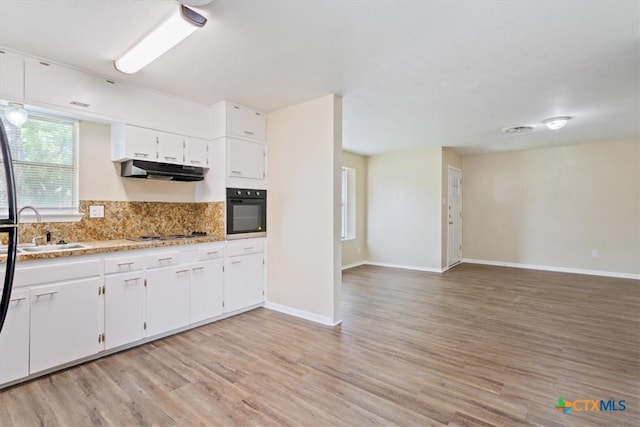 2410 Meadow Ln, Copperas Cove, TX 76522 - kitchen featuring black oven, under cabinet range hood, light wood-style flooring, and backsplash