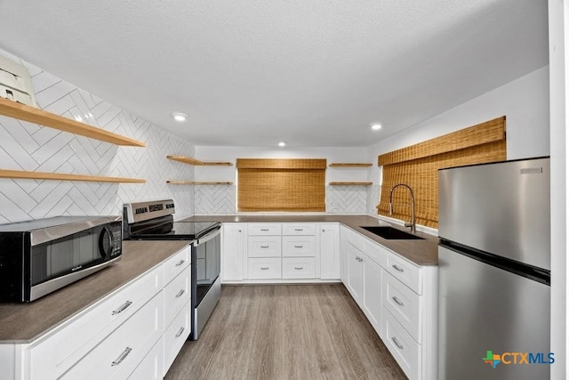 51 Private Road 901, Florence, TX 76527 - kitchen with open shelves, stainless steel appliances, backsplash, light wood-style flooring, and white cabinets