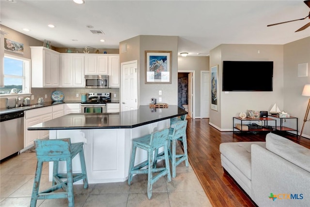 314 Windswept Dr, Port Lavaca, TX 77979 - kitchen with stainless steel appliances, open floor plan, ceiling fan, white cabinetry, and a breakfast bar