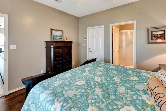 bedroom featuring ensuite bath and dark wood-type flooring