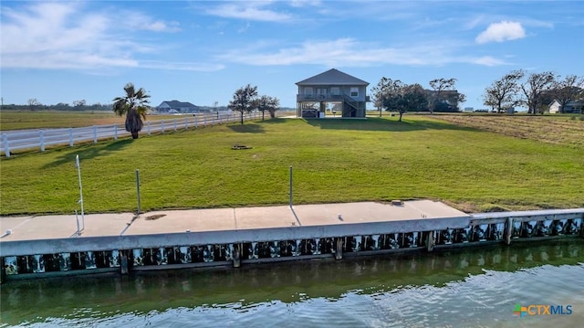 view of dock featuring a yard, a water view, and a rural view