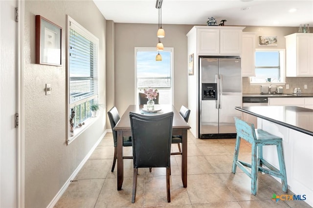 dining space featuring plenty of natural light, light tile patterned flooring, and sink