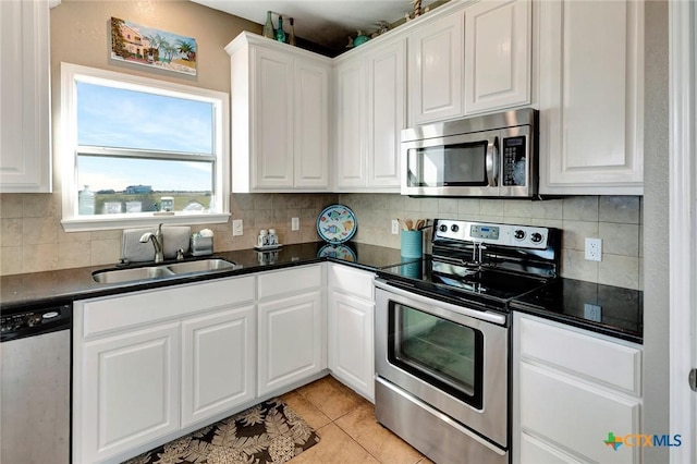 314 Windswept Dr, Port Lavaca, TX 77979 - kitchen featuring appliances with stainless steel finishes, dark countertops, decorative backsplash, white cabinetry, and light tile patterned flooring
