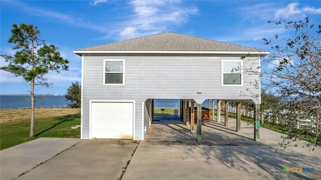 exterior space with a front yard, a water view, a garage, and a carport