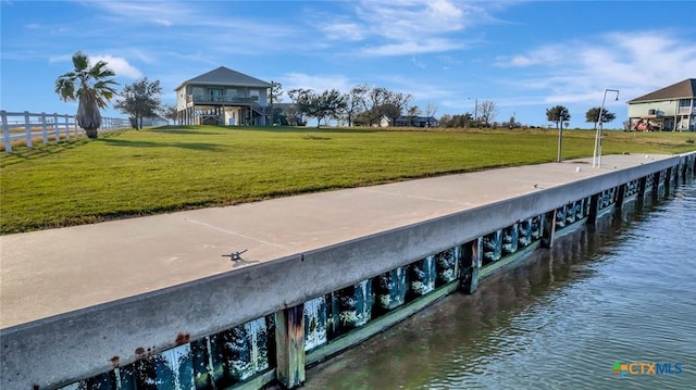 view of dock with a lawn and a water view