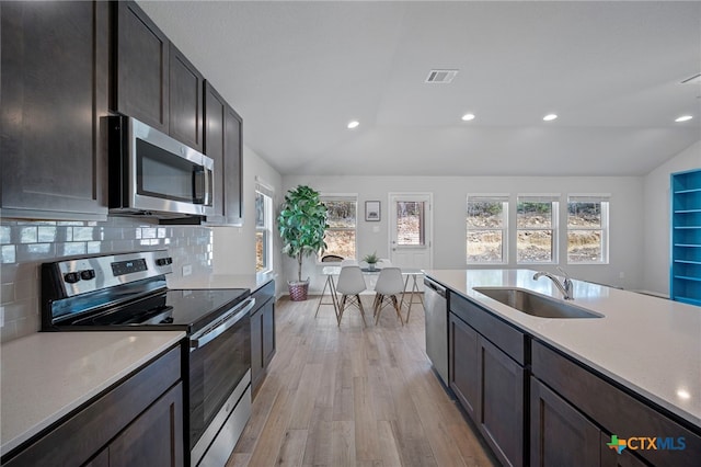 kitchen with stainless steel appliances, vaulted ceiling, a sink, and backsplash