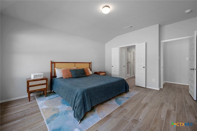 bedroom with lofted ceiling, baseboards, visible vents, and wood finished floors