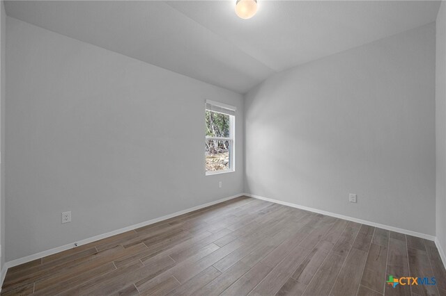 unfurnished room featuring lofted ceiling, baseboards, and wood finished floors