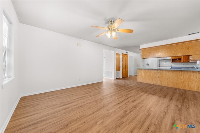 unfurnished living room with sink, hardwood / wood-style floors, and ceiling fan