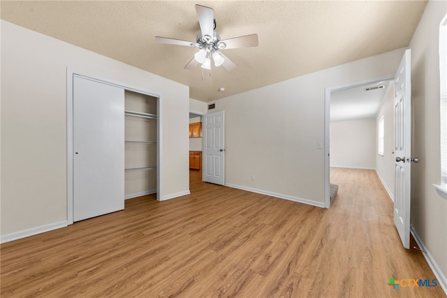 unfurnished bedroom with a textured ceiling, light hardwood / wood-style flooring, ceiling fan, and a closet