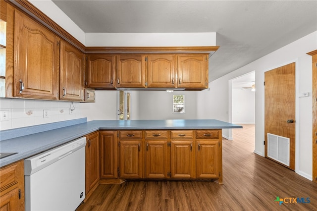 kitchen with white dishwasher, kitchen peninsula, dark hardwood / wood-style floors, ceiling fan, and backsplash