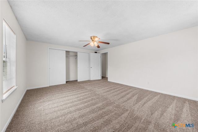 unfurnished bedroom featuring a closet, a textured ceiling, ceiling fan, and carpet floors