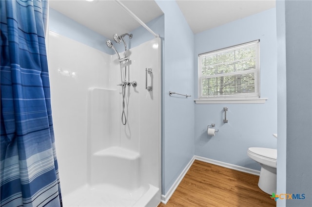 bathroom featuring hardwood / wood-style floors, walk in shower, and toilet