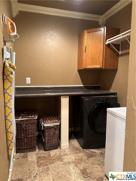 clothes washing area with washer / clothes dryer, ornamental molding, and cabinets