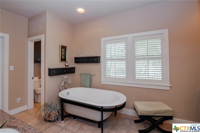 bathroom with a tub, tile patterned flooring, toilet, and sink