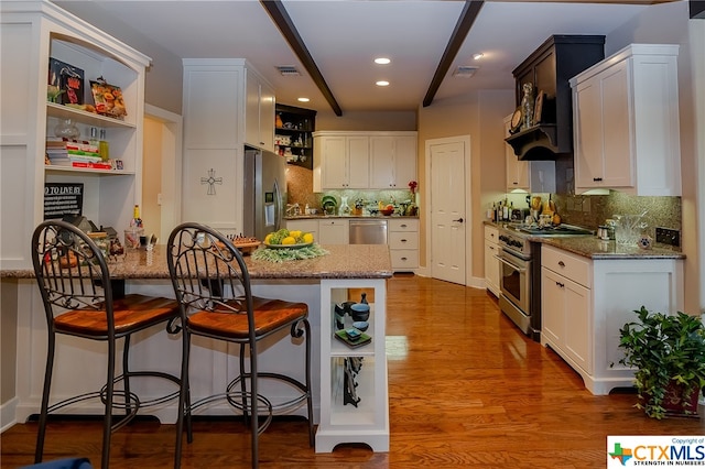 kitchen with light stone counters, appliances with stainless steel finishes, tasteful backsplash, light hardwood / wood-style flooring, and white cabinets