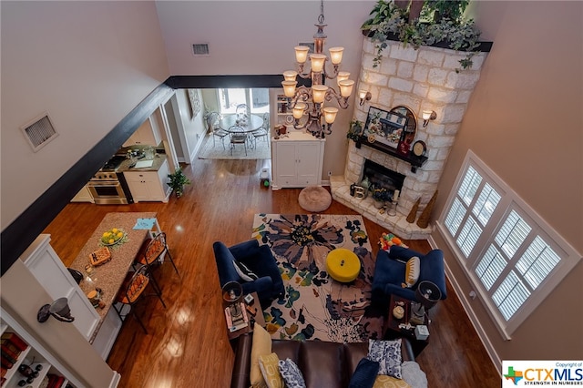 living room with a fireplace, a high ceiling, dark hardwood / wood-style floors, and a chandelier