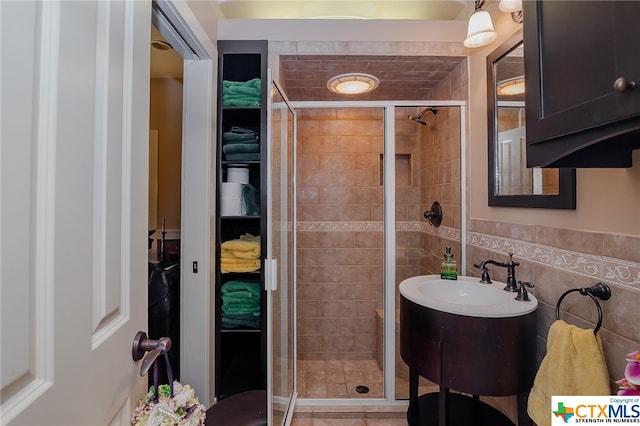 bathroom featuring vanity, tile walls, and a shower with shower door