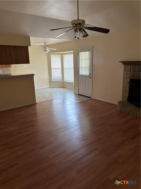 unfurnished living room with ceiling fan, a fireplace, and light hardwood / wood-style flooring