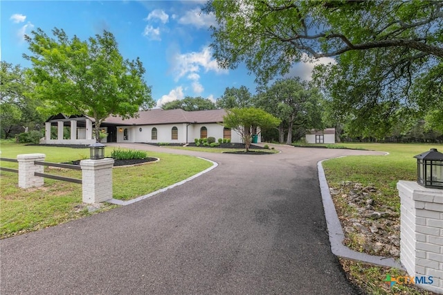ranch-style house with curved driveway and a front lawn