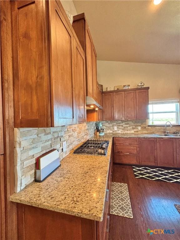 174 Riley Ln, Port Oconnor, TX 77982 - kitchen with a sink, stainless steel gas stovetop, brown cabinets, dark wood finished floors, and decorative backsplash