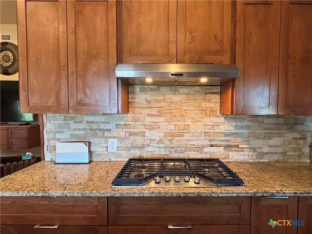 174 Riley Ln, Port Oconnor, TX 77982 - kitchen with stainless steel gas stovetop, under cabinet range hood, tasteful backsplash, and light stone counters