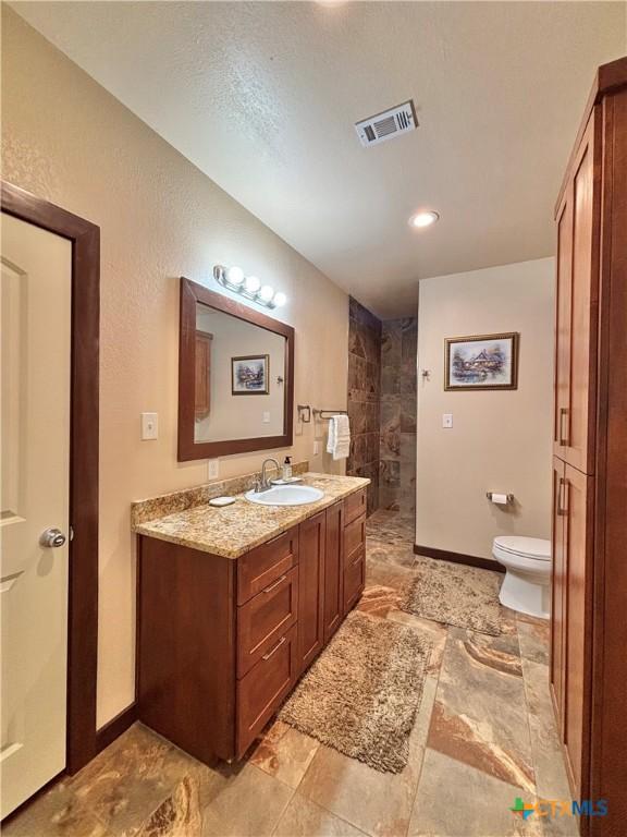 174 Riley Ln, Port Oconnor, TX 77982 - bathroom featuring toilet, a walk in shower, vanity, baseboards, and recessed lighting