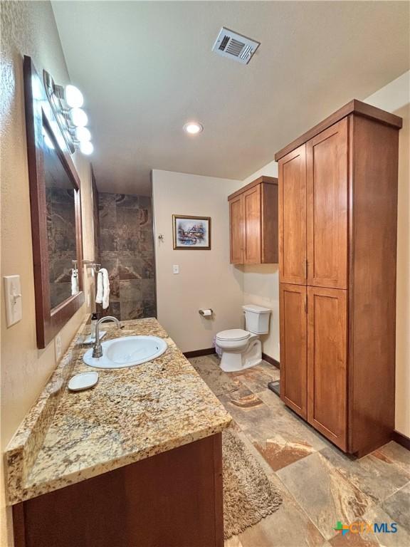 174 Riley Ln, Port Oconnor, TX 77982 - full bath with baseboards, vanity, toilet, stone finish flooring, and recessed lighting