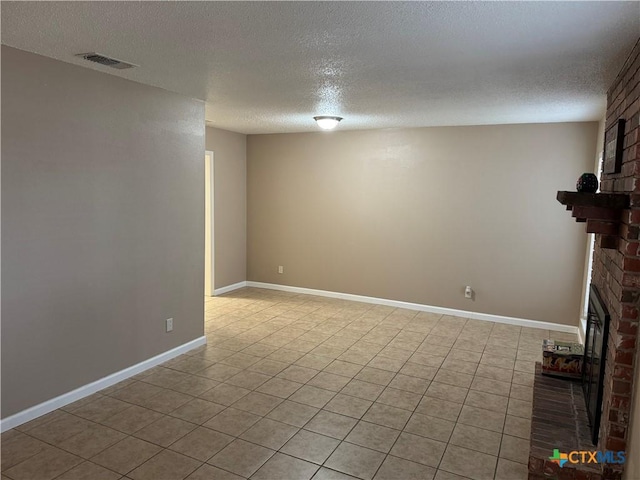 basement with a brick fireplace, a textured ceiling, and light tile patterned flooring