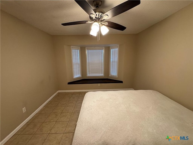 unfurnished bedroom with ceiling fan and tile patterned flooring