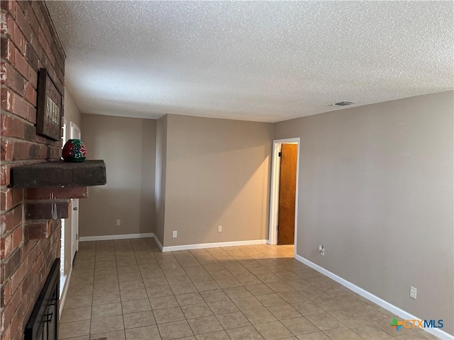 unfurnished living room featuring a textured ceiling, light tile patterned flooring, and a large fireplace