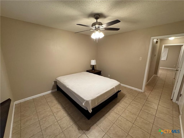 unfurnished bedroom with ceiling fan, light tile patterned floors, and a textured ceiling