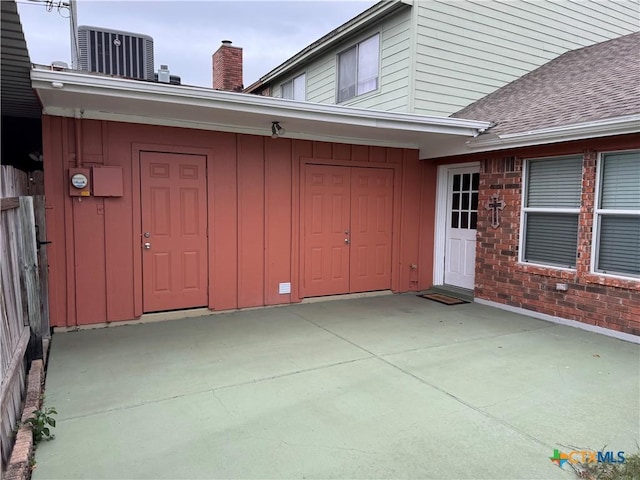 view of exterior entry with central AC and a patio area