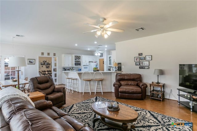 living room with hardwood / wood-style flooring, ornamental molding, and ceiling fan