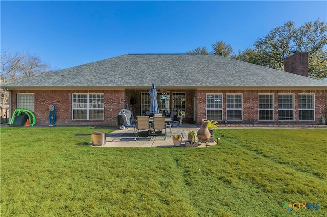 rear view of house with a patio and a lawn