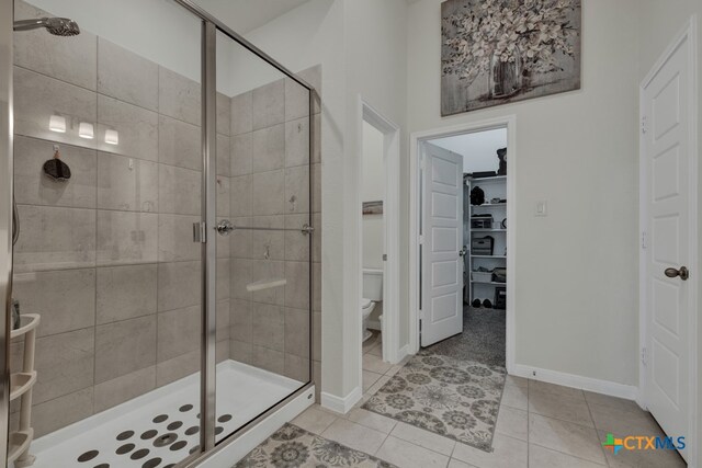 bathroom featuring toilet, an enclosed shower, and tile patterned flooring