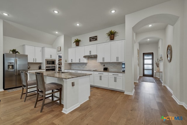 kitchen with light wood-type flooring, appliances with stainless steel finishes, a center island with sink, and white cabinets