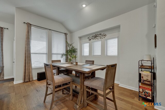 dining area featuring vaulted ceiling, light hardwood / wood-style floors, and plenty of natural light