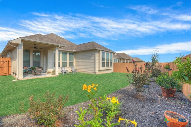 back of property with ceiling fan, a yard, and a patio area