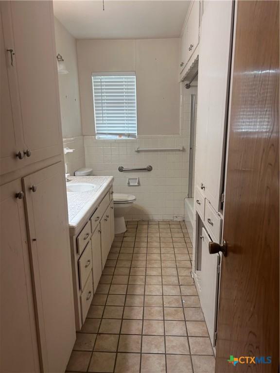 205 S College St, Troy, TX 76579 - bathroom with tile patterned floors, vanity, tile walls, and a wainscoted wall