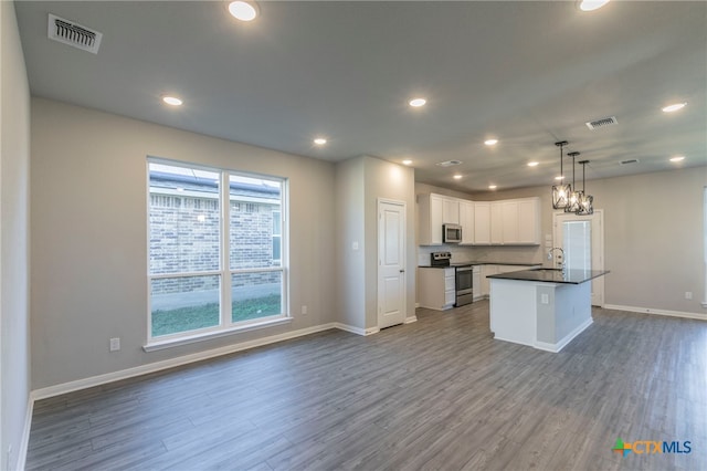 kitchen with white cabinets, appliances with stainless steel finishes, a center island with sink, and hanging light fixtures