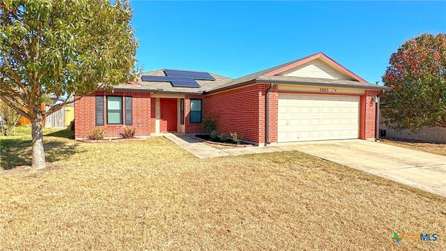 ranch-style home featuring a garage, a front yard, and solar panels