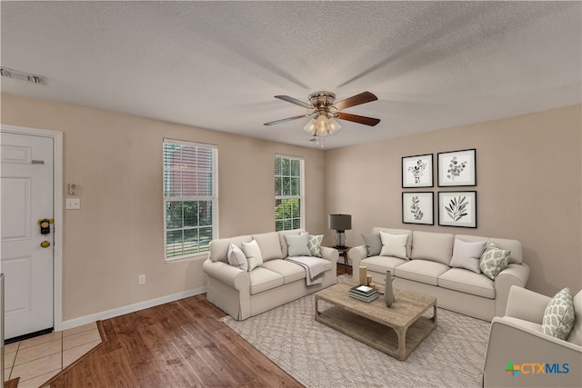 living room with hardwood / wood-style floors, ceiling fan, and a textured ceiling