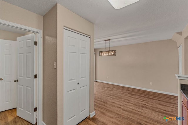 corridor with a textured ceiling and hardwood / wood-style flooring