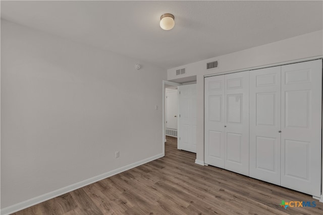 unfurnished bedroom with a closet and hardwood / wood-style floors