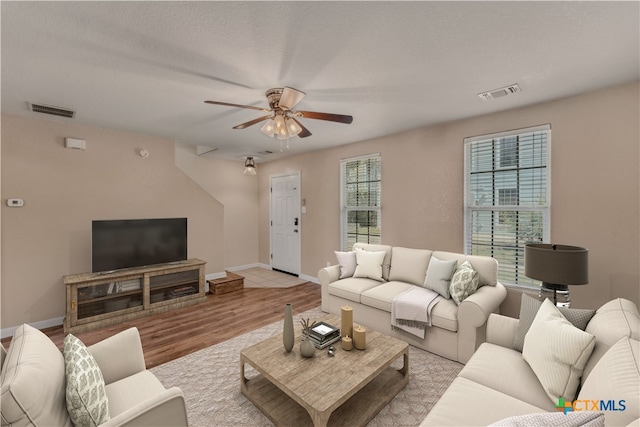 living room with ceiling fan, a textured ceiling, and light hardwood / wood-style floors