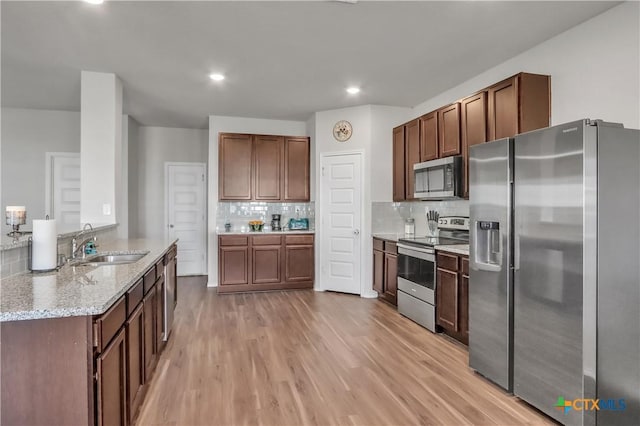 2425 Marty Way, Seguin, TX 78155 - kitchen with appliances with stainless steel finishes, backsplash, light wood-style flooring, light stone countertops, and recessed lighting