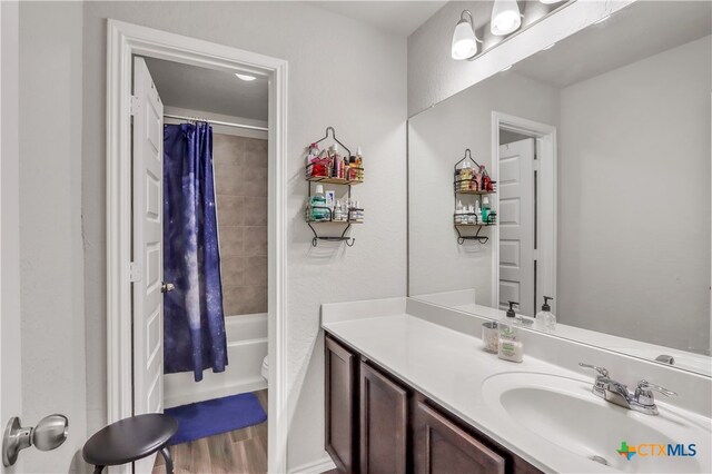 full bathroom featuring wood-type flooring, shower / bath combo with shower curtain, toilet, and vanity