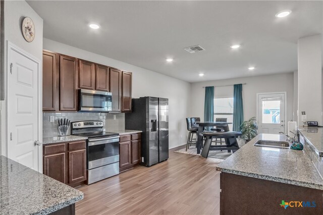 kitchen featuring stainless steel appliances, sink, light wood-type flooring, and dark brown cabinetry